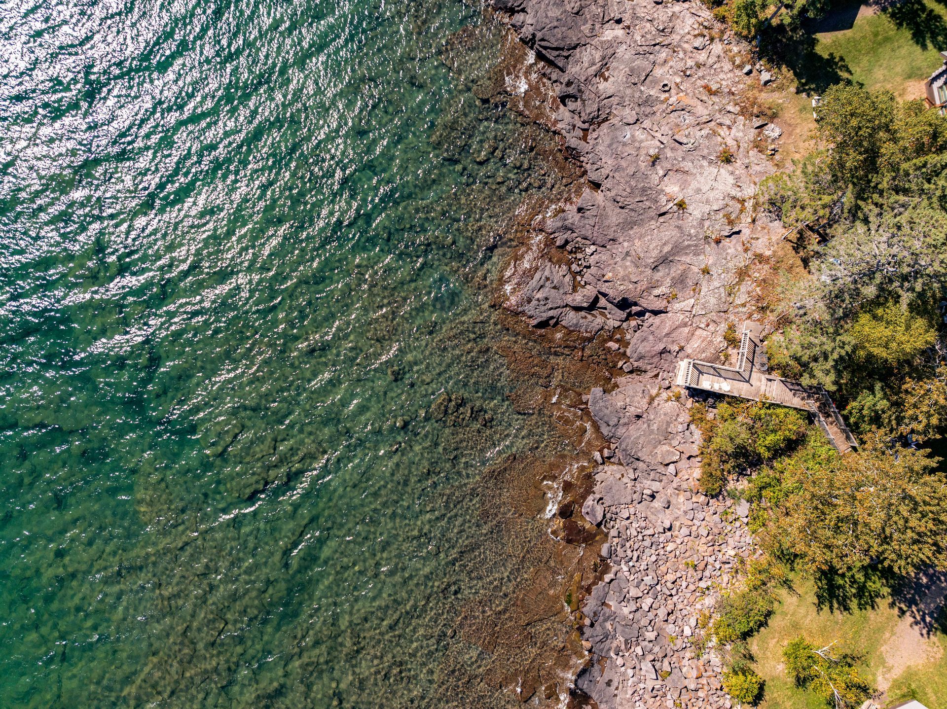 An aerial view of a lake with a rocky shoreline and trees.