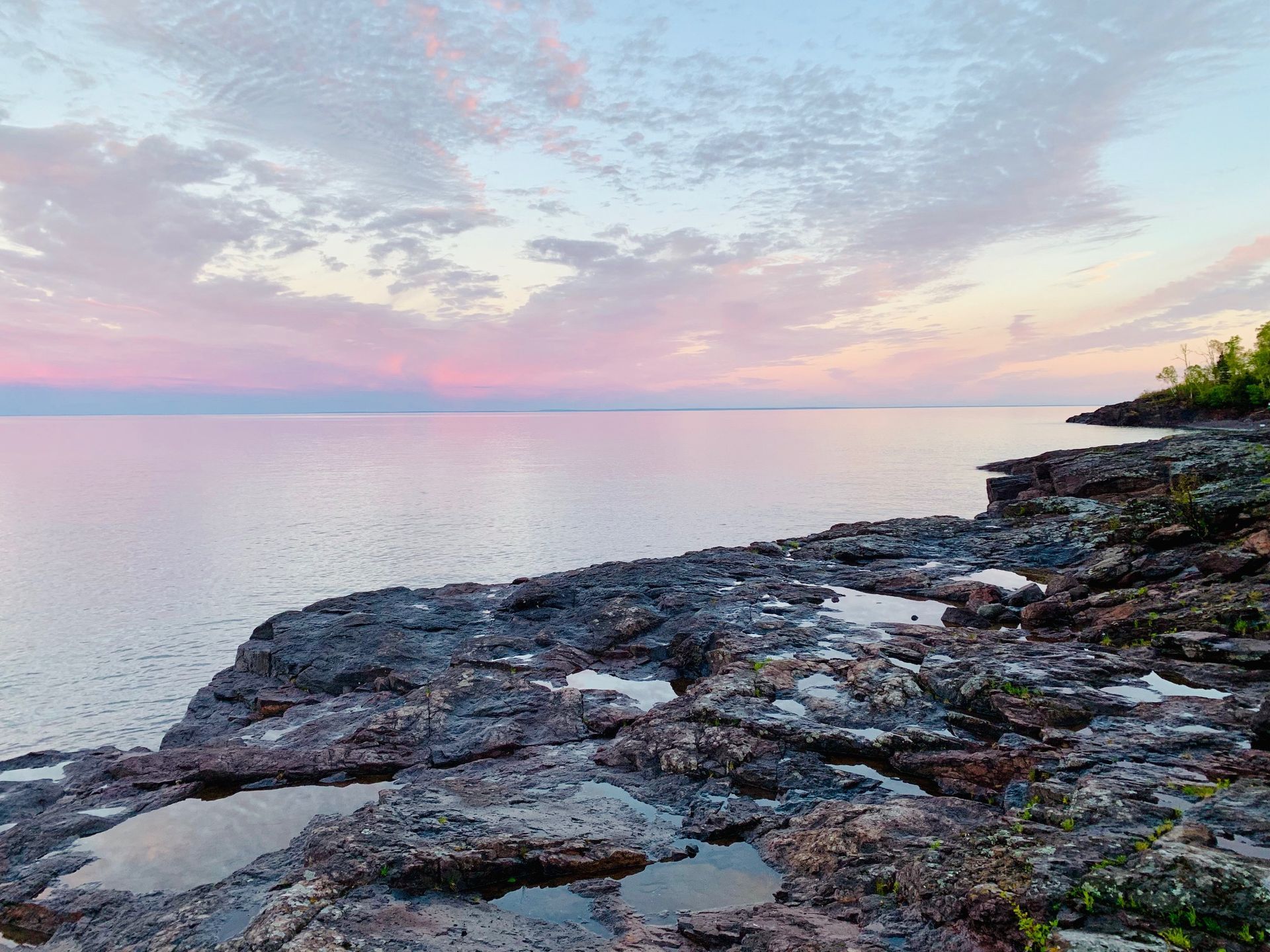 A cliff overlooking a body of water with a sunset in the background.