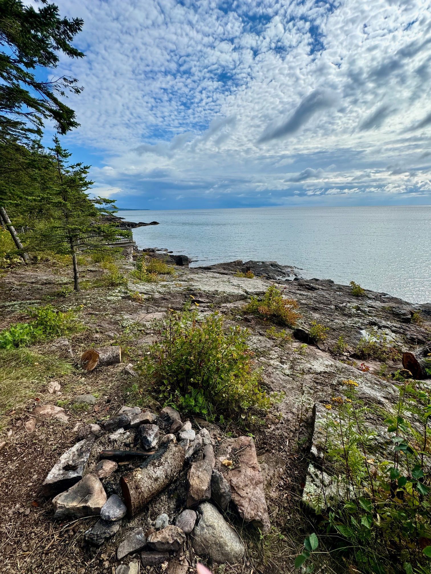 There is a fire pit on the shore of the ocean.