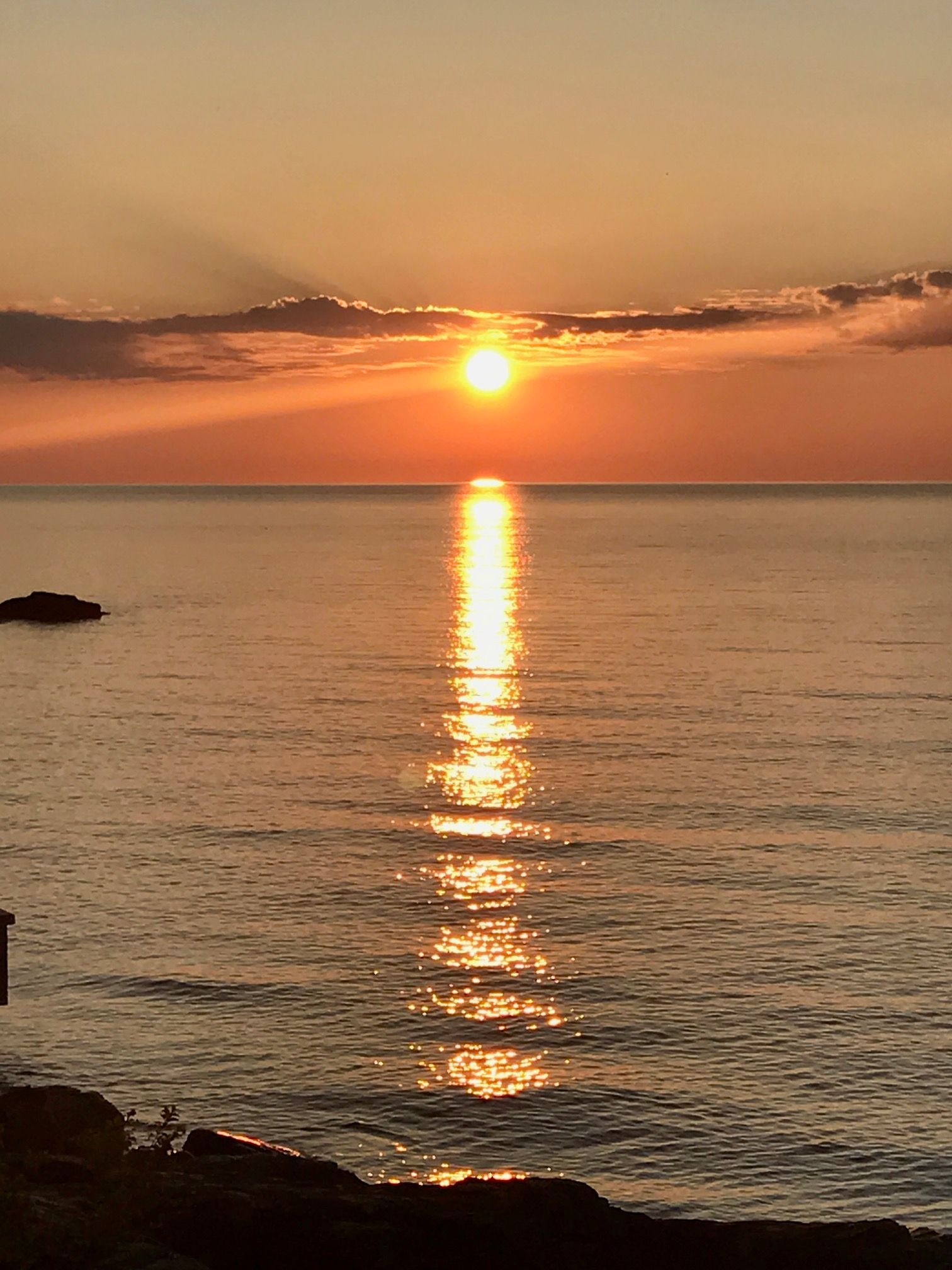 The sun is setting over the ocean and reflecting in the water.