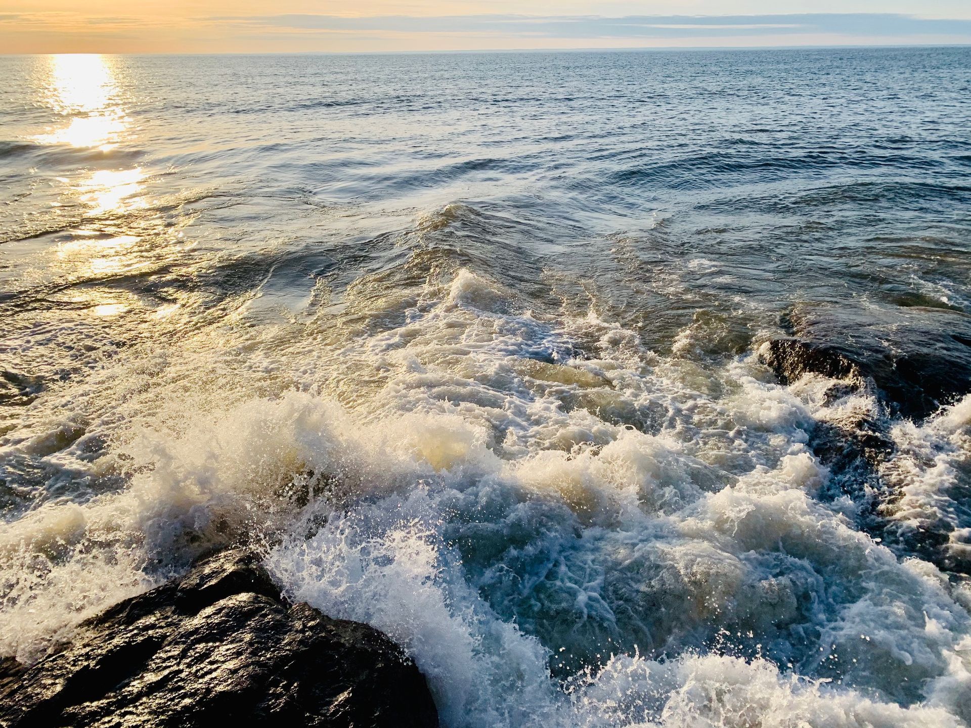A large body of water with waves crashing on a rocky shore.