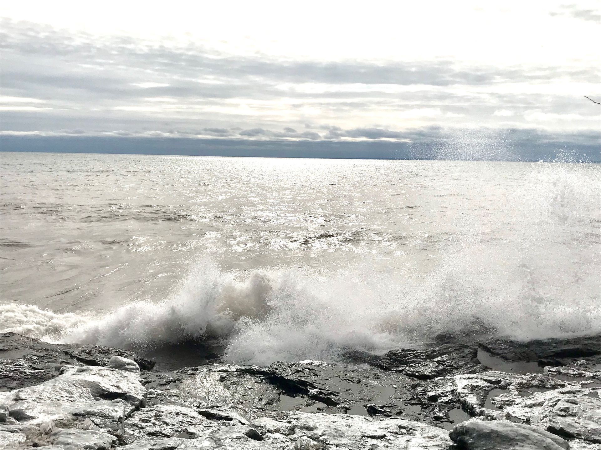 A black and white photo of waves crashing on a rocky beach.