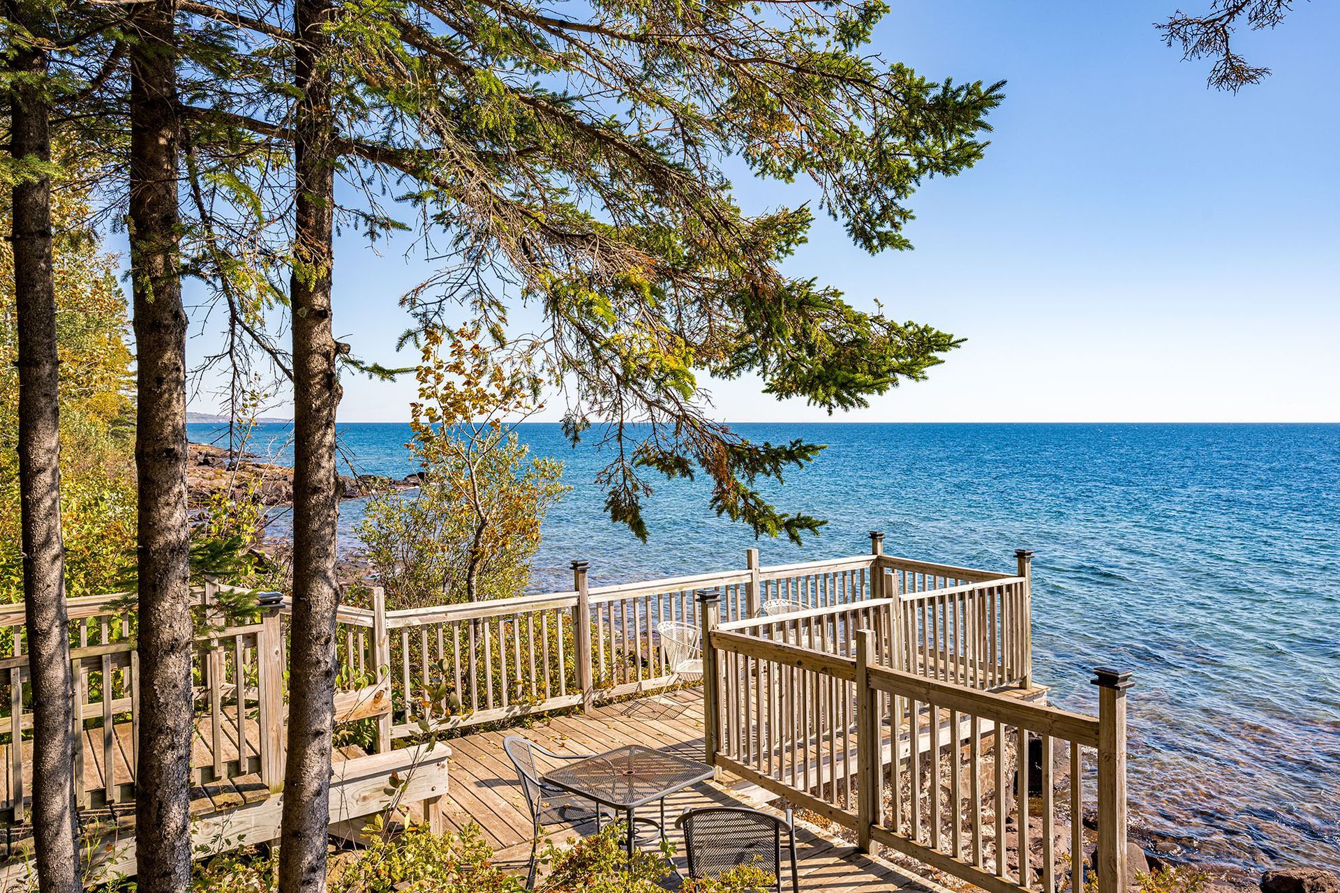 A wooden deck overlooking a body of water surrounded by trees.