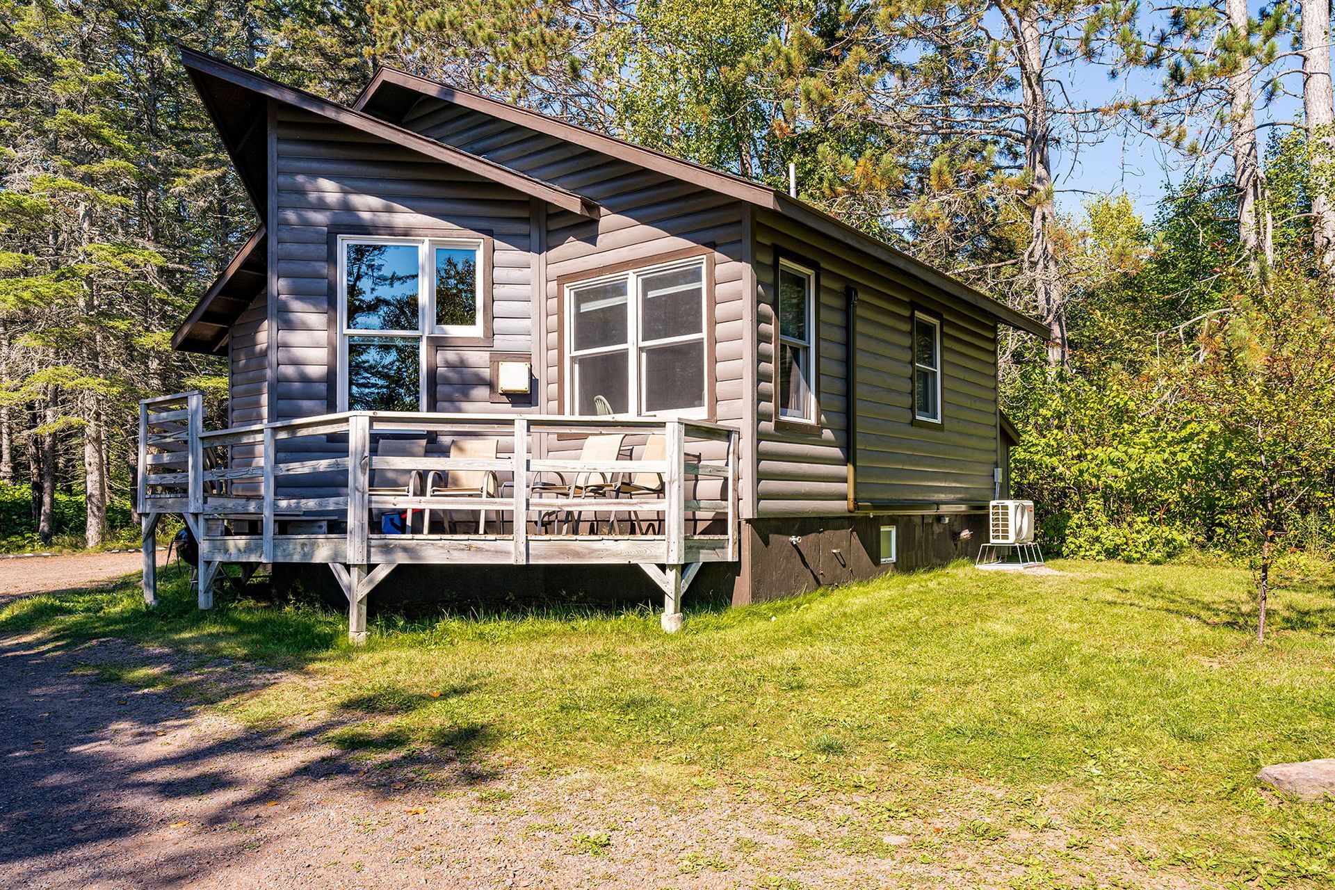 A small cabin with a large deck in the middle of the woods.