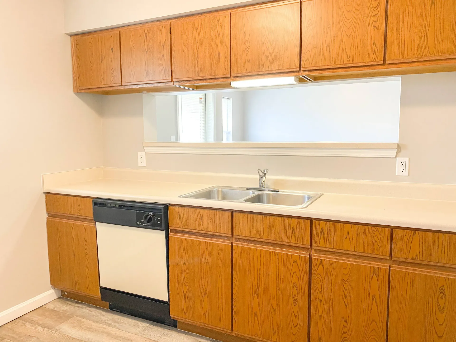 Kitchen with wood cabinetry, double stainless steel sink, and built-in dishwasher.