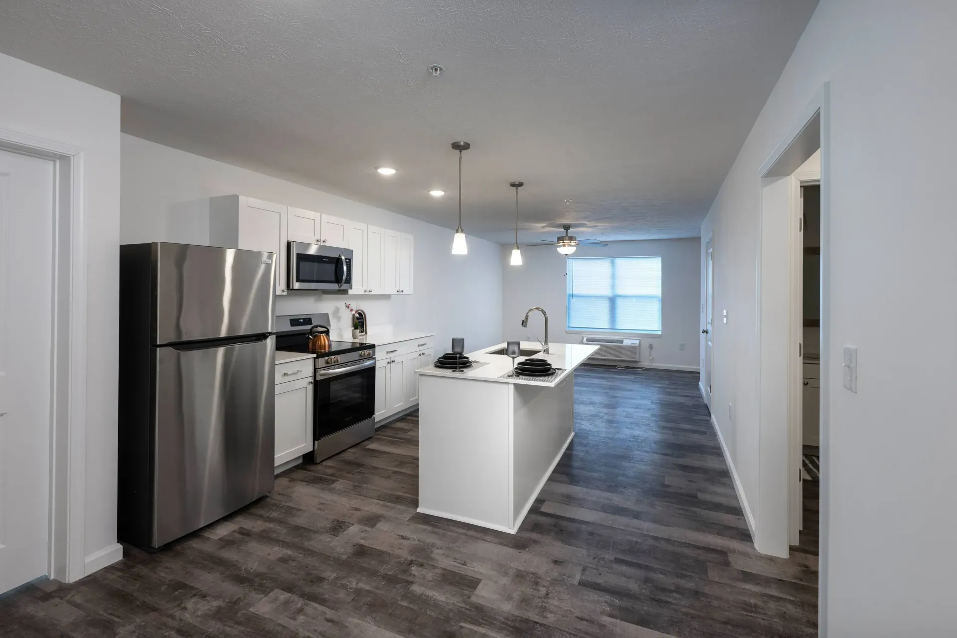 Open-concept kitchen with white cabinets, stainless steel refrigerator, and an island.