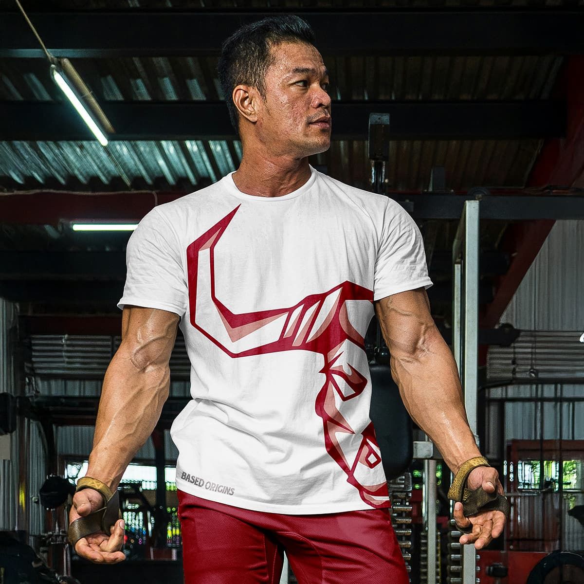 A man stands in a gym wearing a shirt with a red bull logo design.