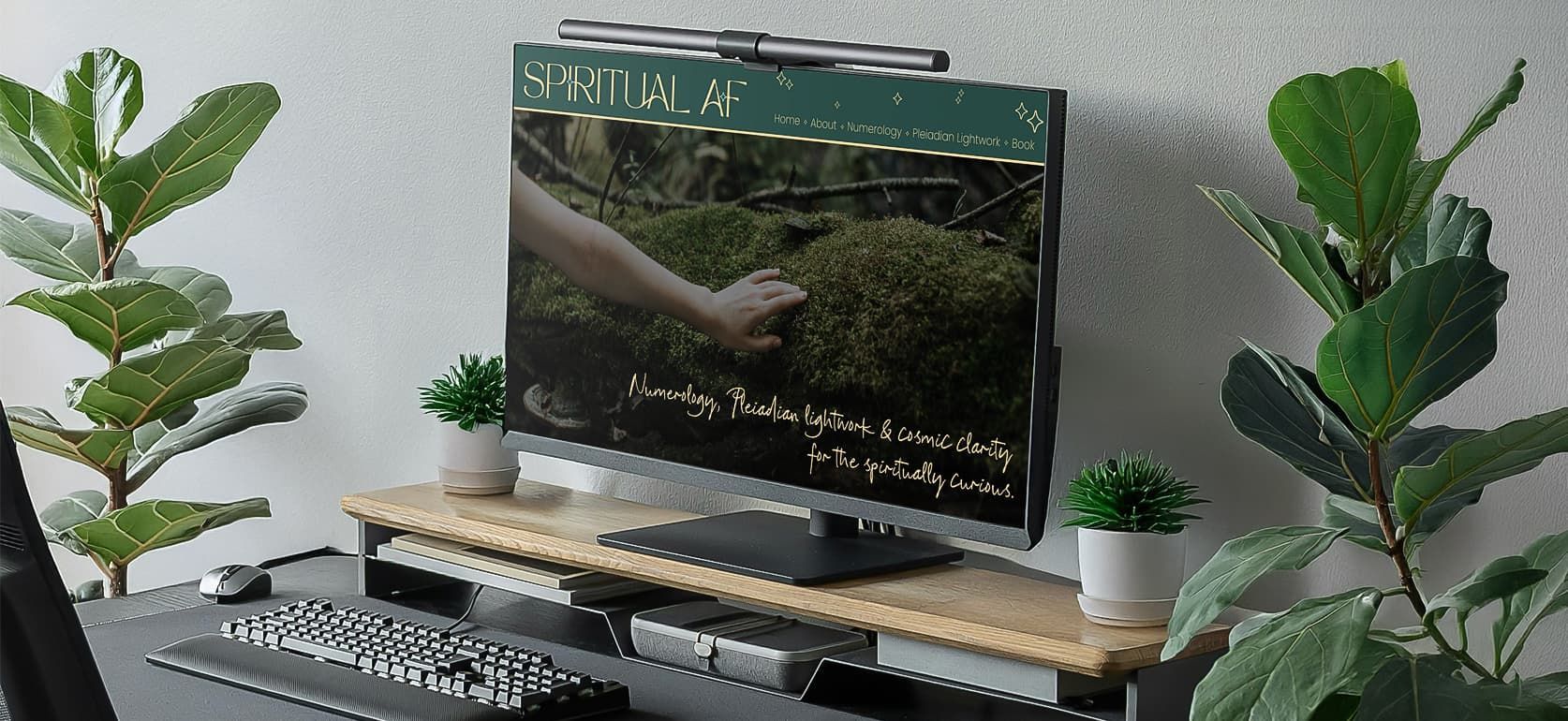 A computer monitor is sitting on top of a wooden desk with a custom website design for spiritual af