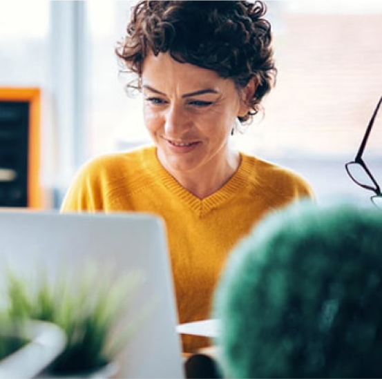 A woman in a yellow sweater is using a laptop computer.