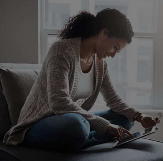 A woman is sitting on a couch using a laptop computer.