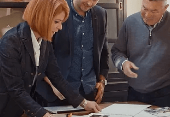 A group of people are standing around a table looking at a piece of paper.