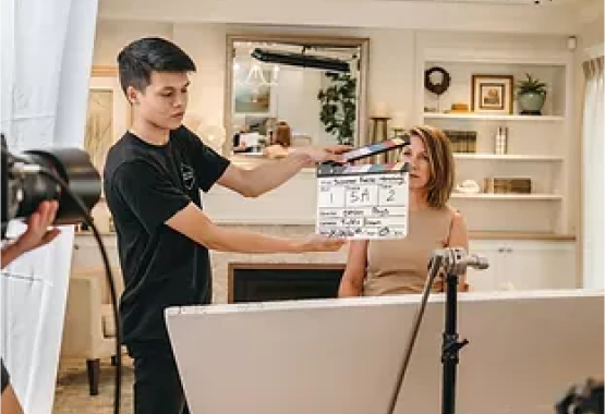 A man is holding a clapper board in front of a woman.