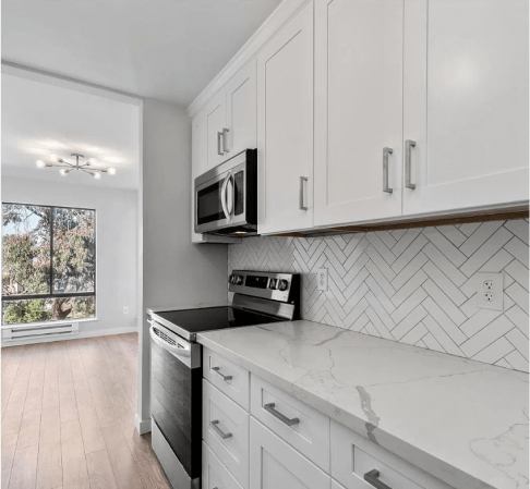 A kitchen with white cabinets and a stove and microwave