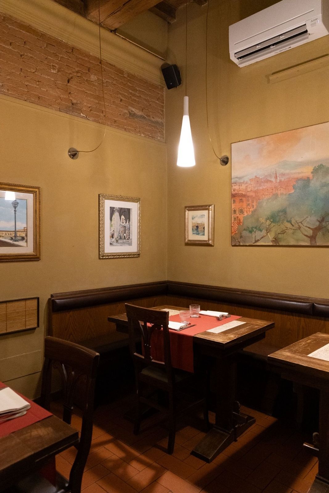 Accogliente angolo ristorante con posti a sedere, quadri incorniciati e luci calde.