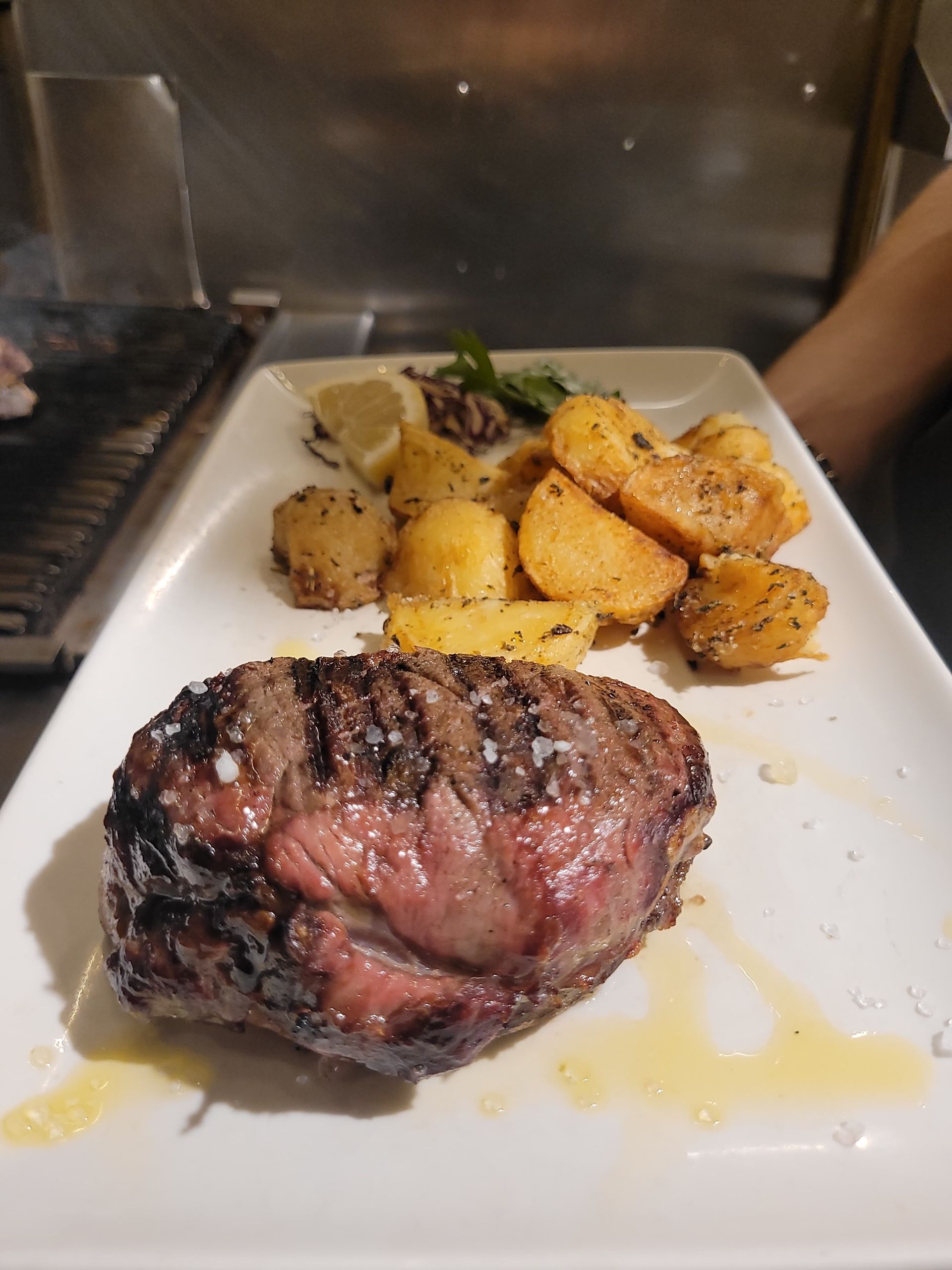 Bistecca alla griglia con patate arrosto su un piatto bianco.