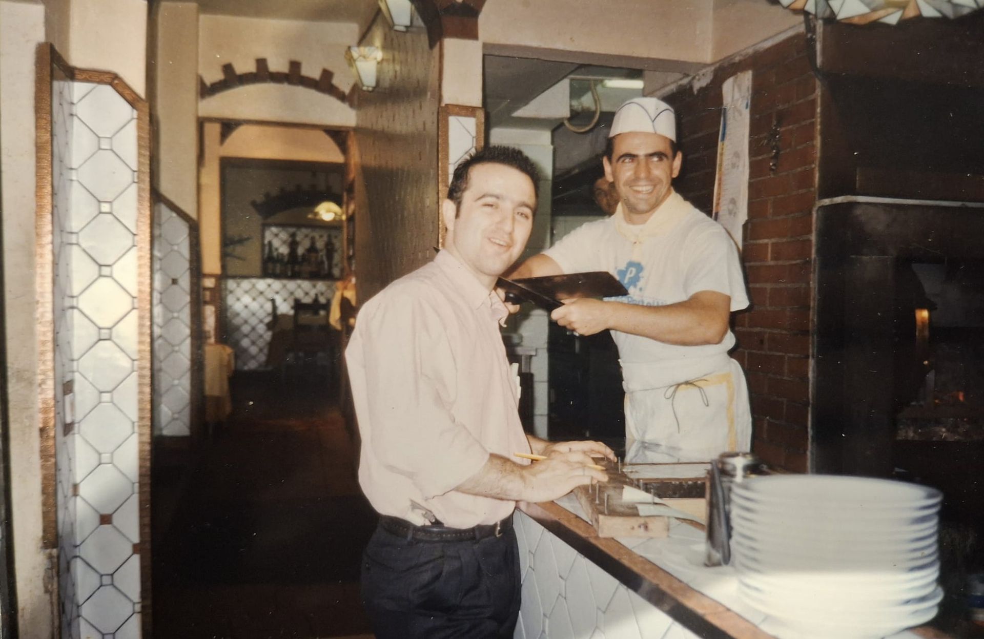 Due uomini in un ristorante. Uno prende un ordine al bancone; l'altro, uno chef, tiene in mano un tablet.