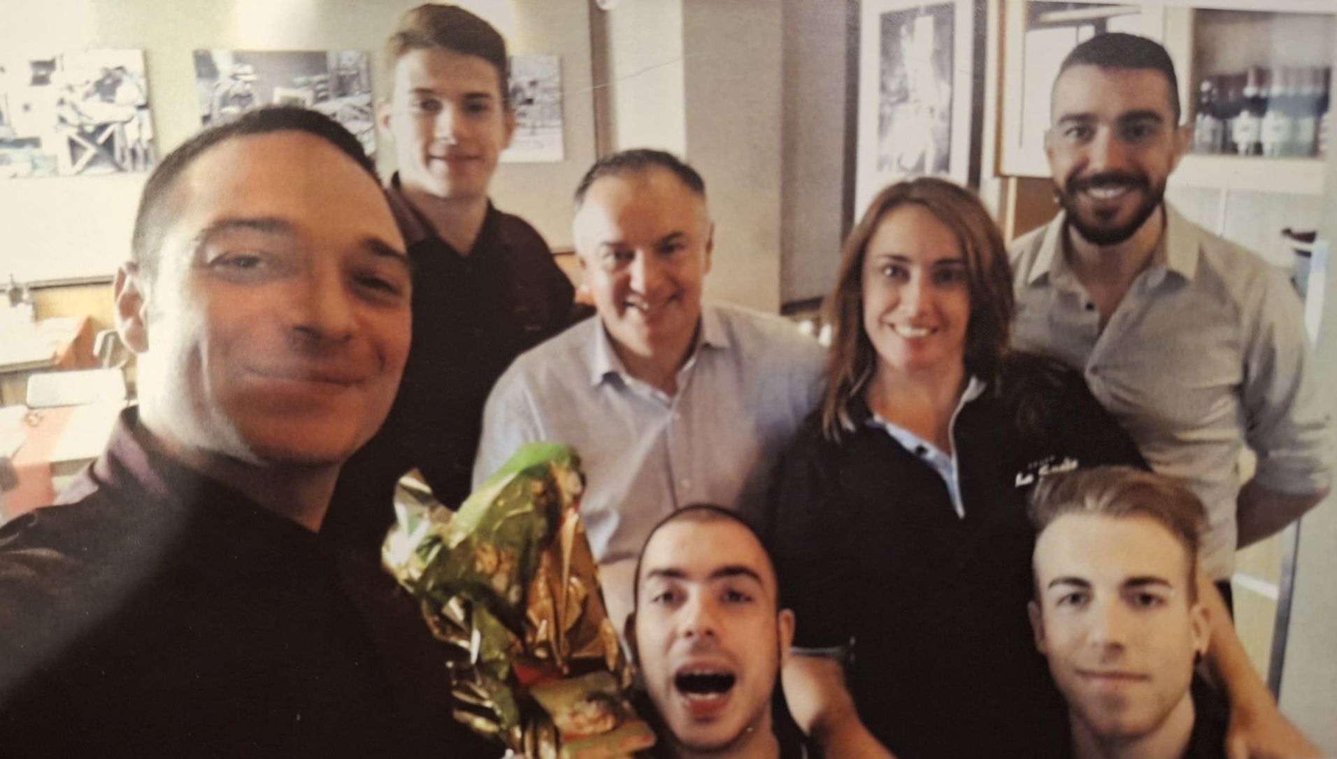 Foto di gruppo di sette persone, per lo più sorridenti, in un ristorante.