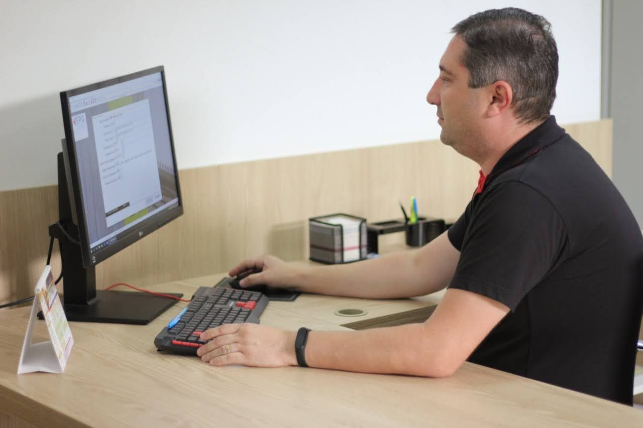 Um homem está sentado em uma mesa usando um computador.