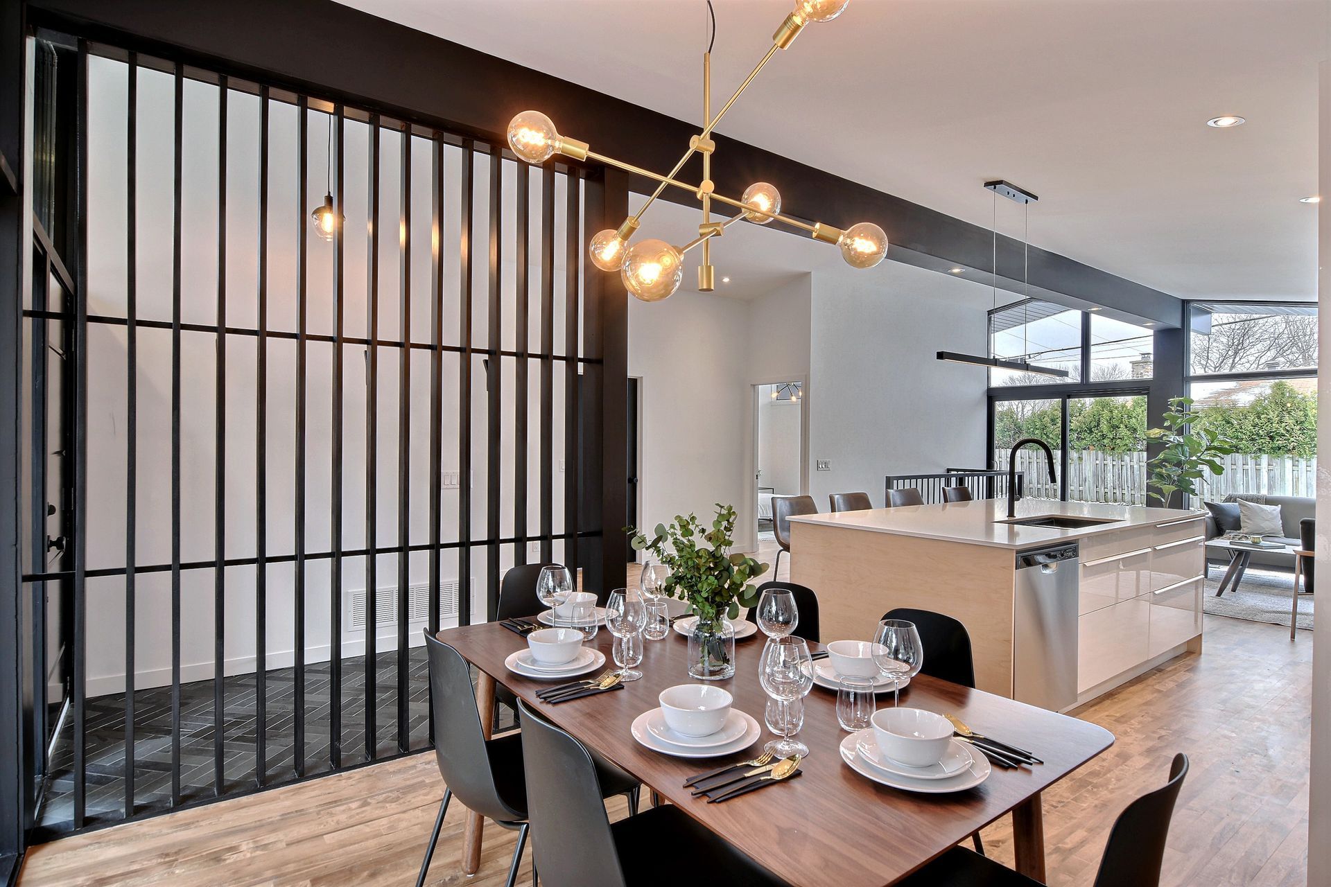 Une salle à manger avec une table et des chaises et une cuisine en arrière-plan.