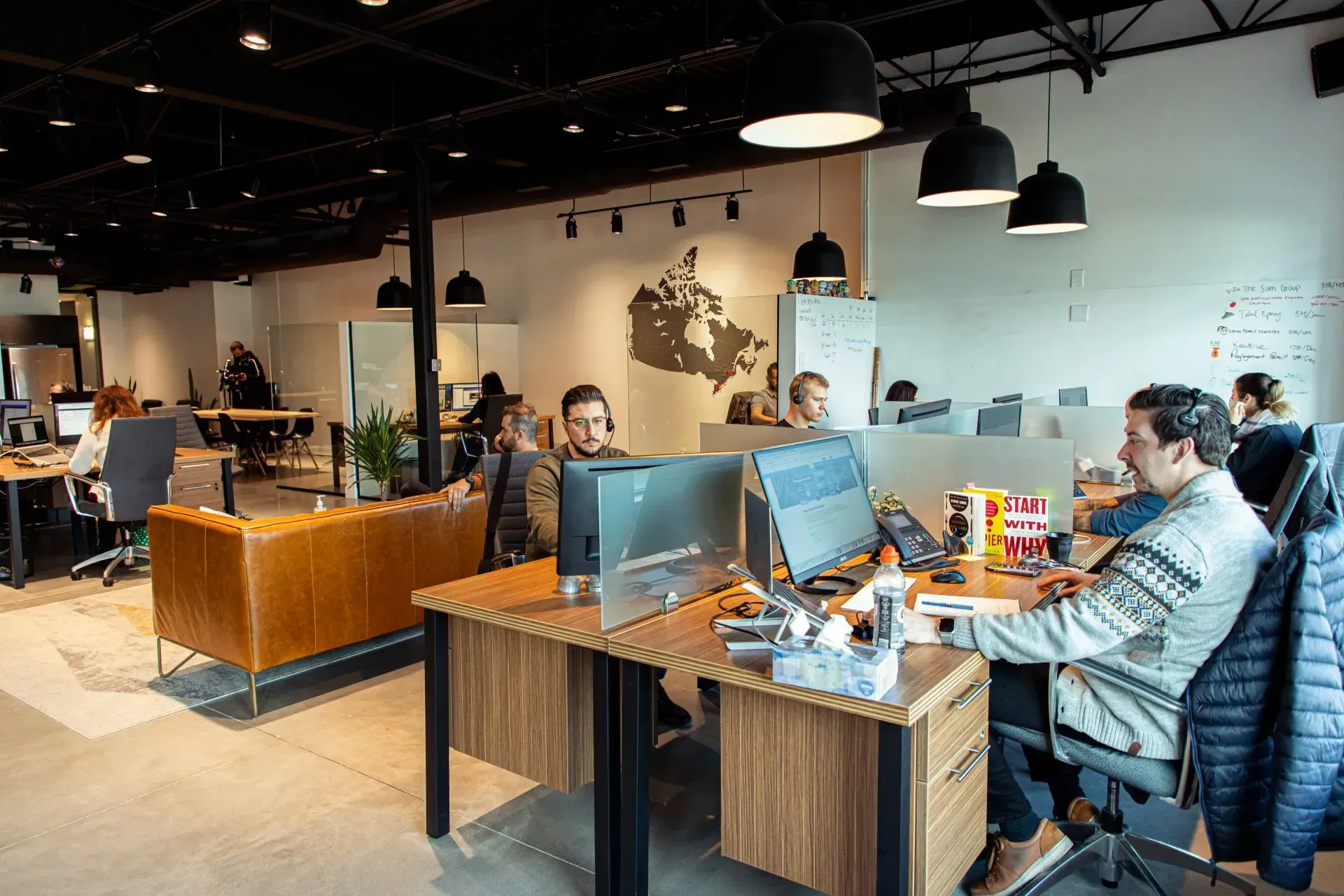 Un groupe de personnes sont assises à des bureaux dans un bureau et travaillent sur des ordinateurs.