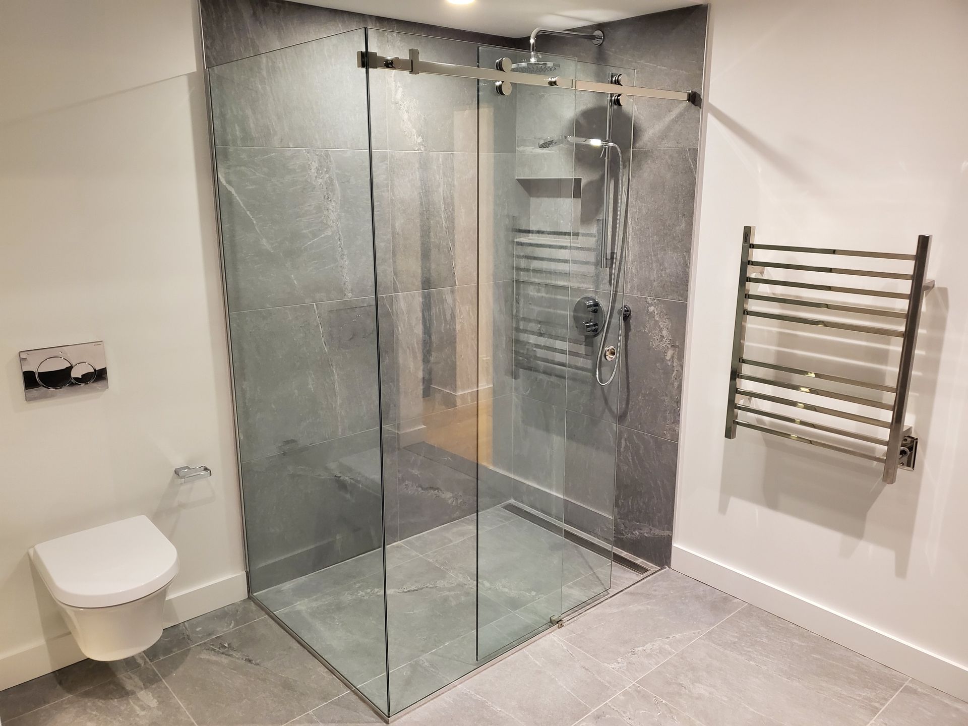 Une salle de bain avec douche à l'italienne, WC et sèche-serviettes.