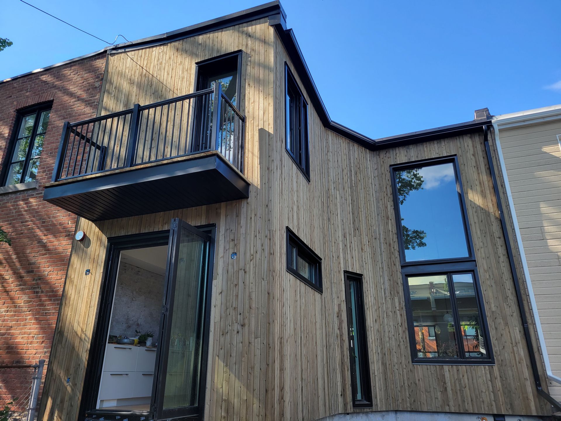 Une maison en bois avec un balcon et beaucoup de fenêtres.