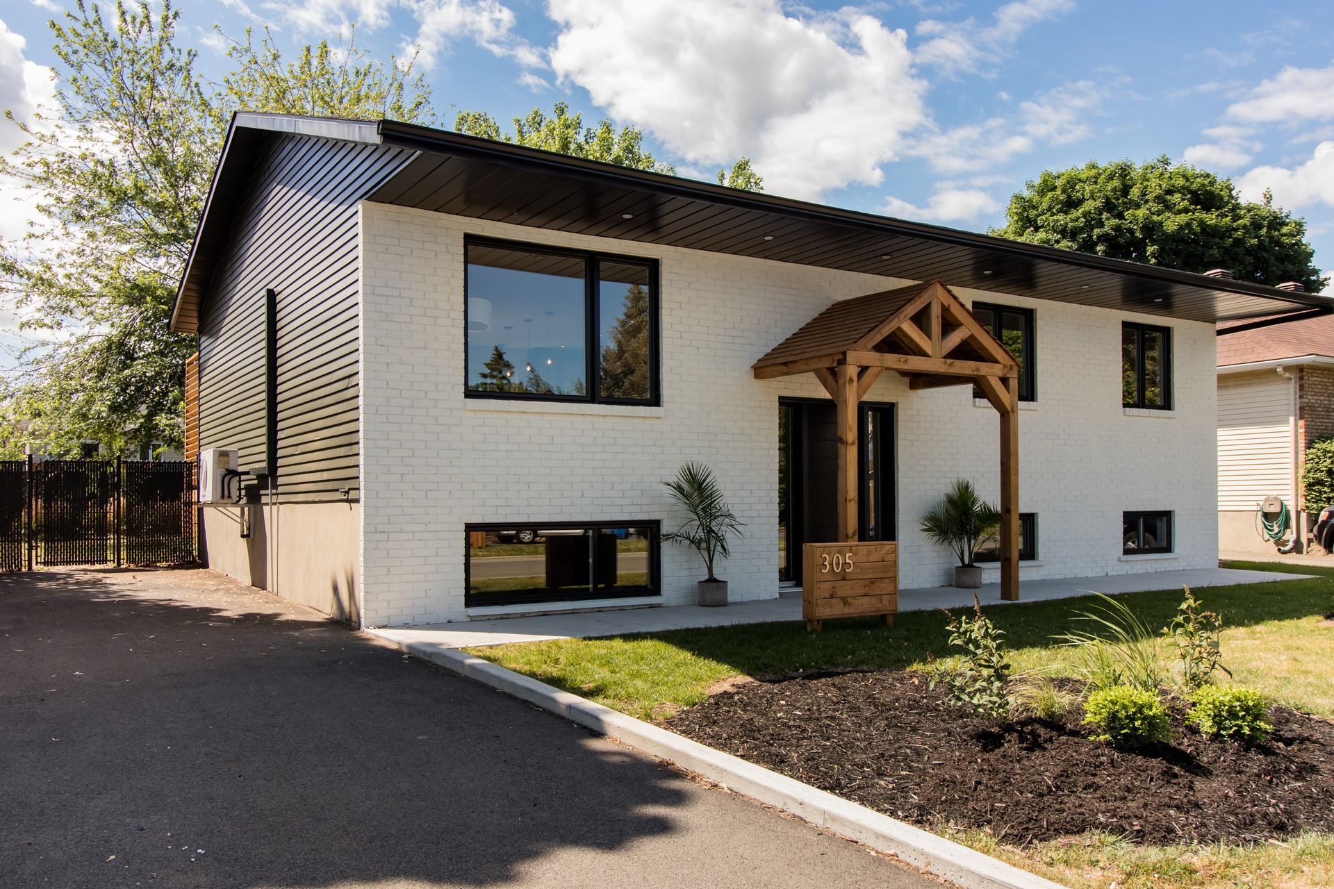 Une maison blanche avec un porche en bois et beaucoup de fenêtres