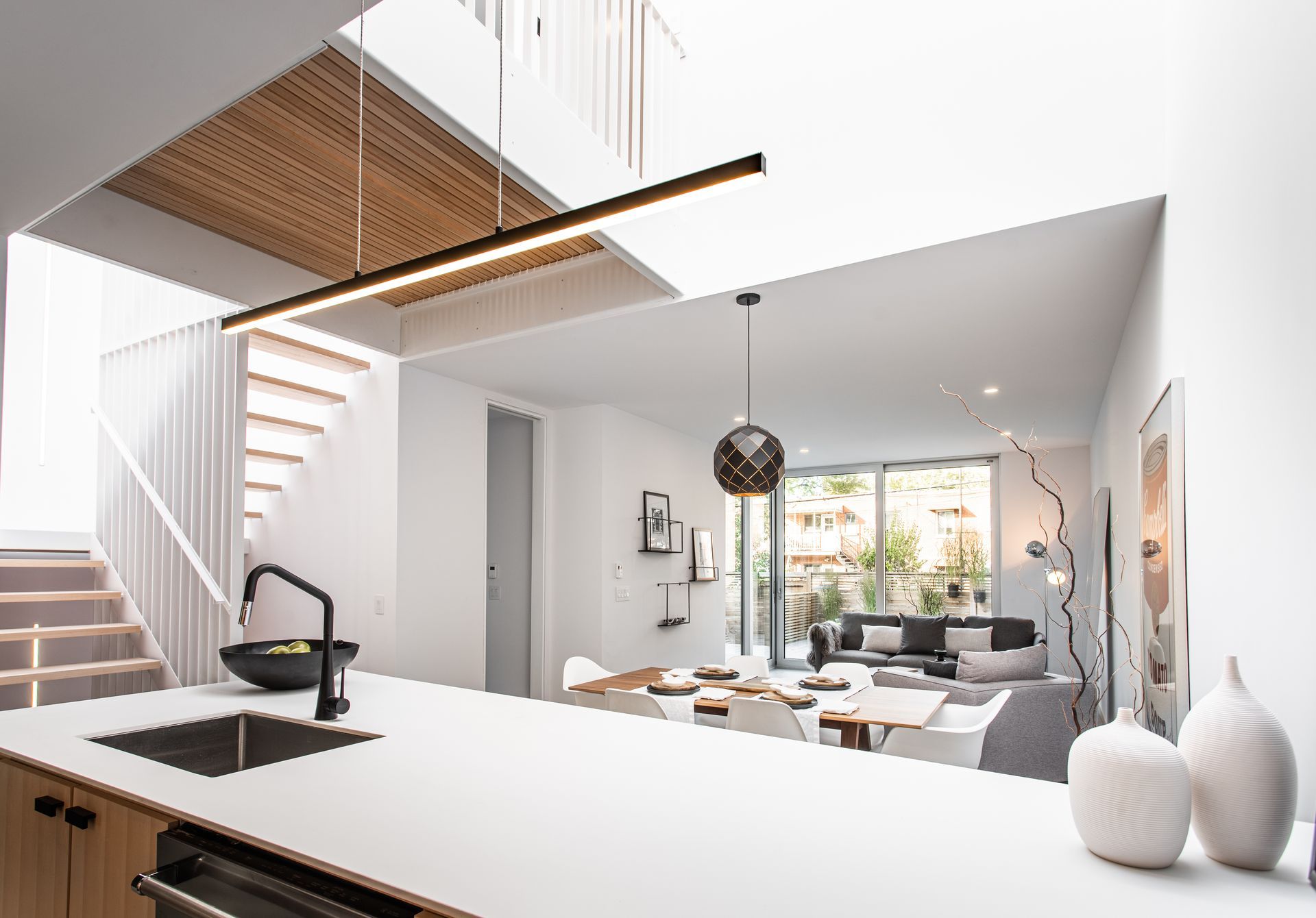 Une cuisine avec un évier, un lave-vaisselle et un escalier menant à un salon.