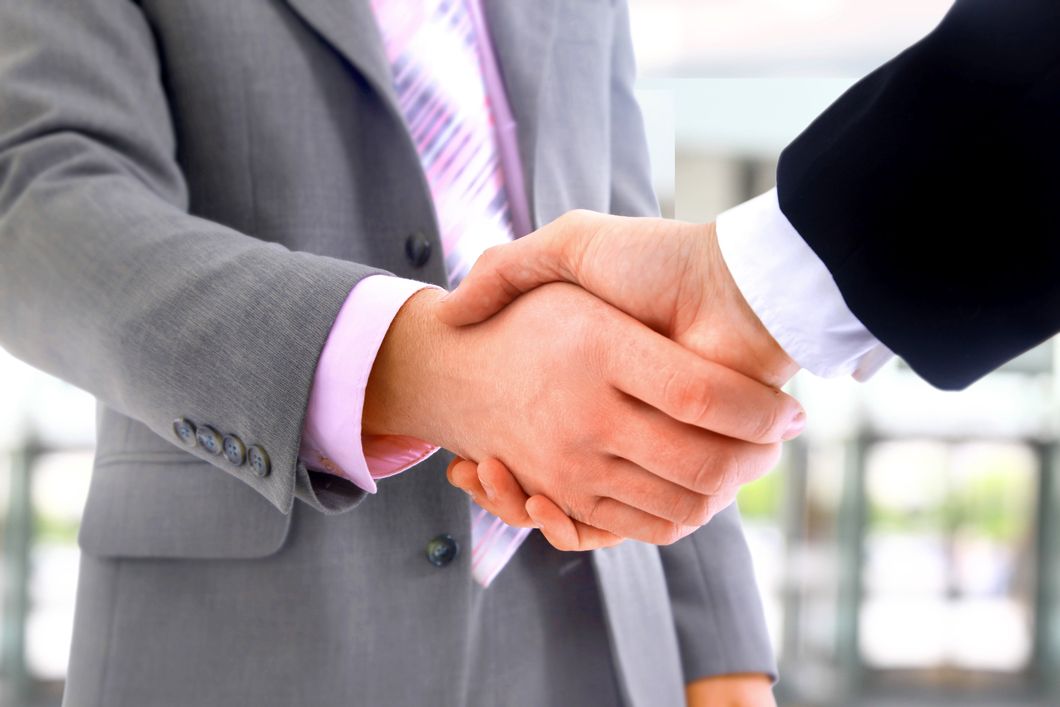 a man in a suit and tie shakes hands with another man