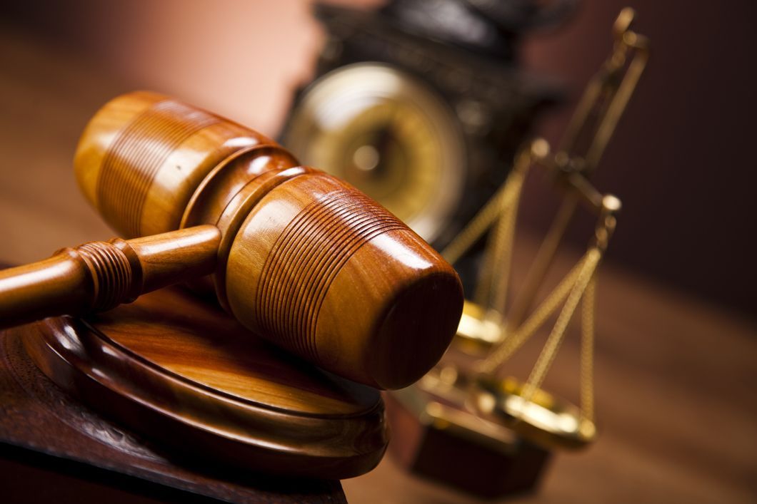 a wooden judge 's gavel and scales of justice on a wooden table