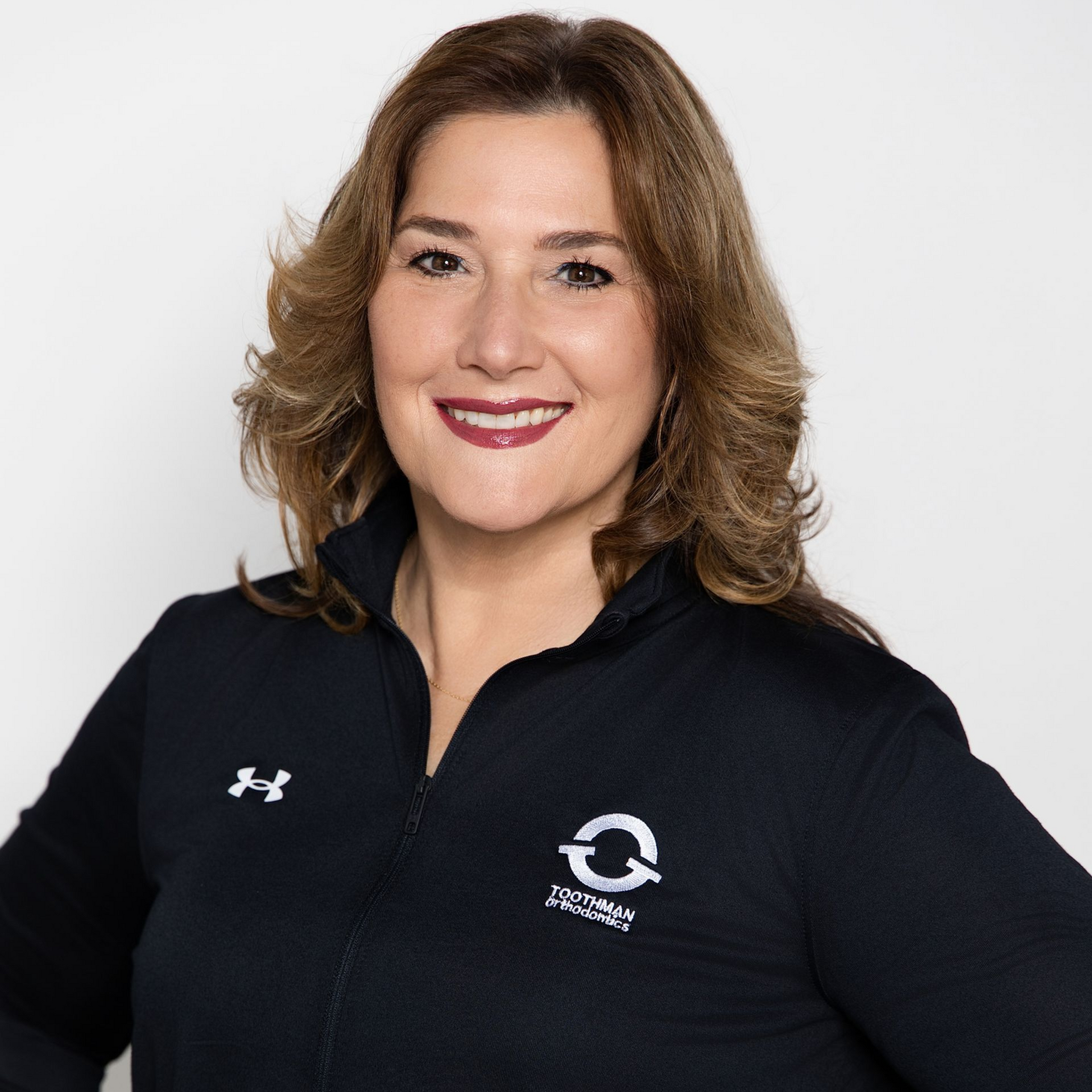 Woman in a black pullover smiling against a white background.