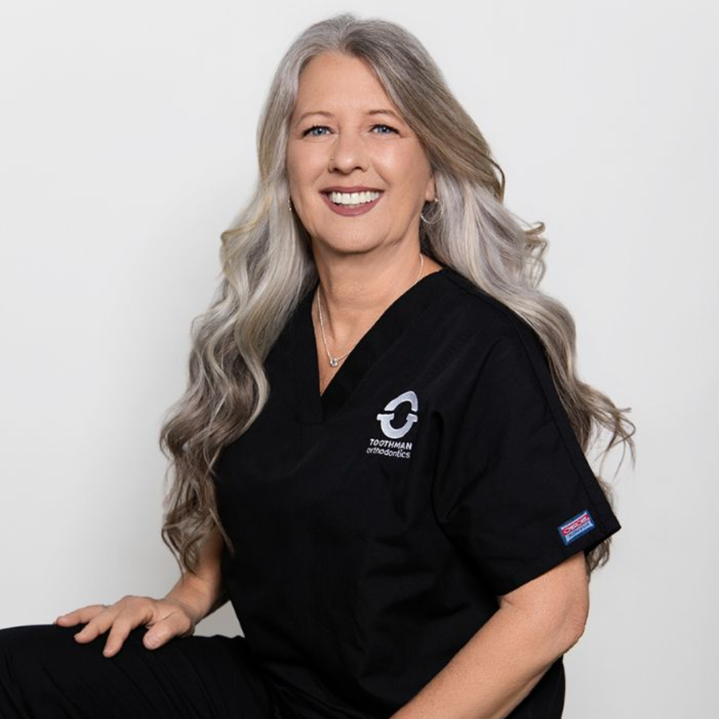 Smiling professional in black polo, seated against a white background.