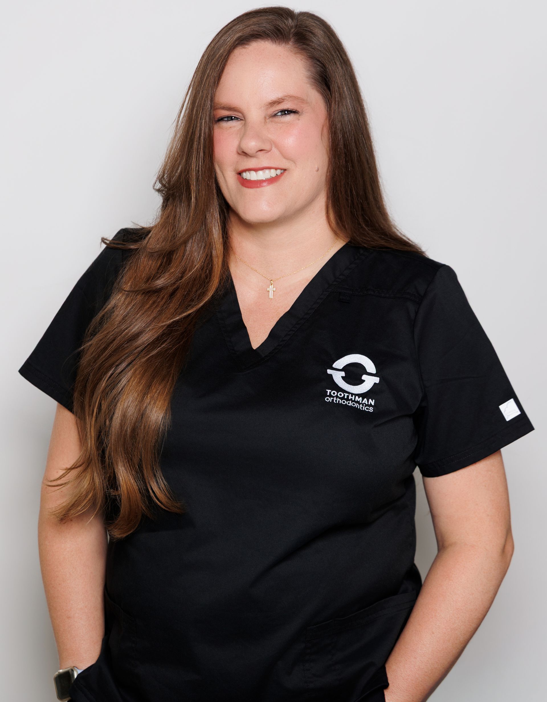 Woman in black scrubs smiling against a light gray background