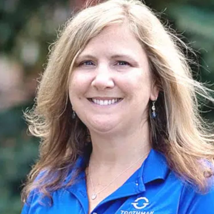 A woman in a blue shirt is smiling for the camera.