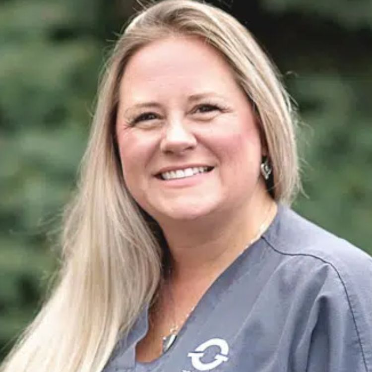 A woman wearing a scrub top is smiling for the camera.