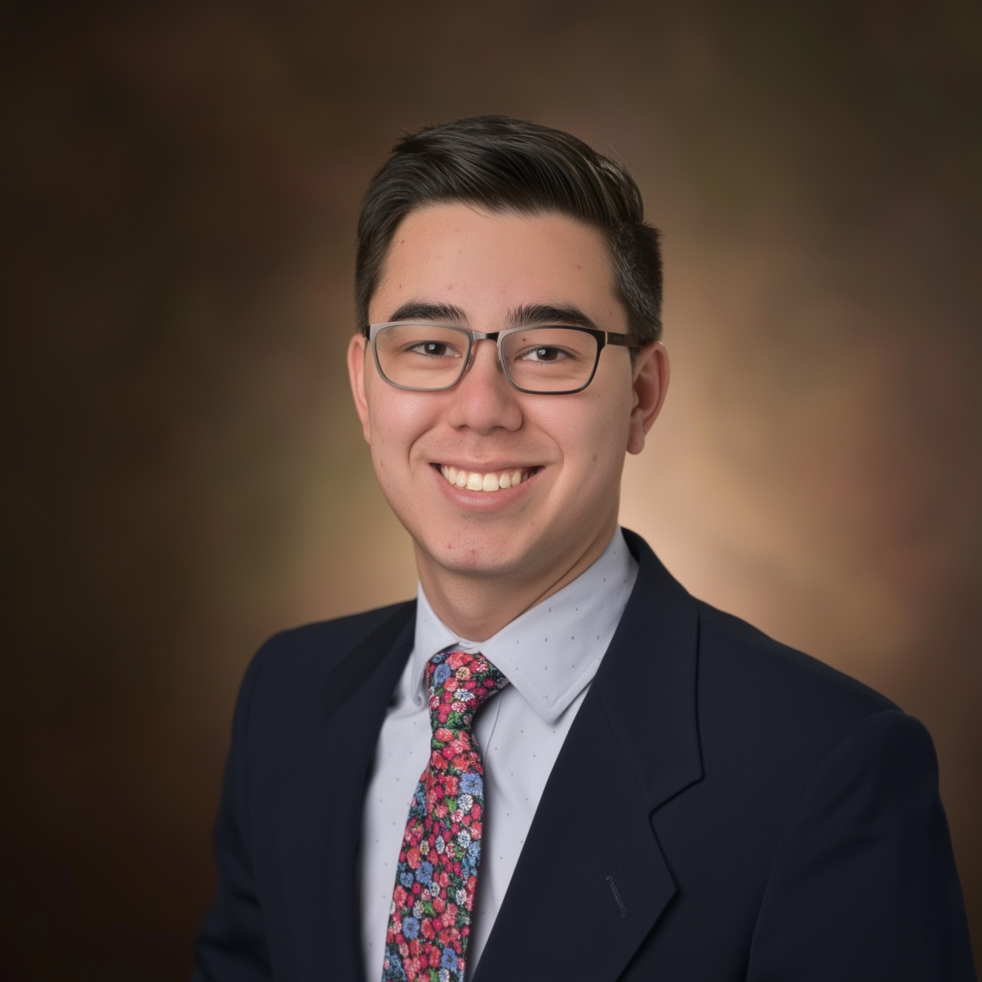 A young man wearing a suit and tie is smiling for the camera.