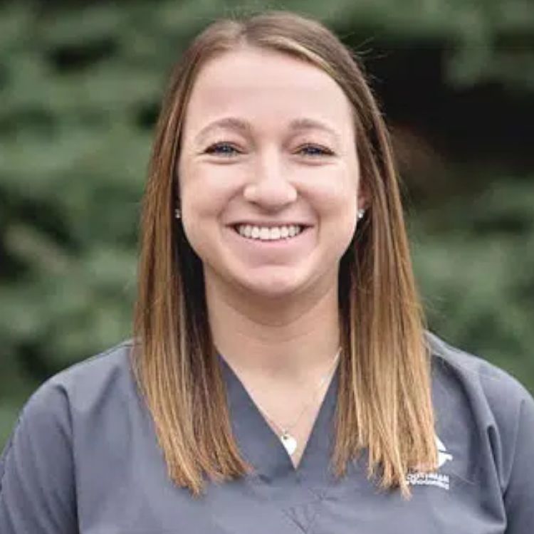 A woman in a scrub top is smiling for the camera.
