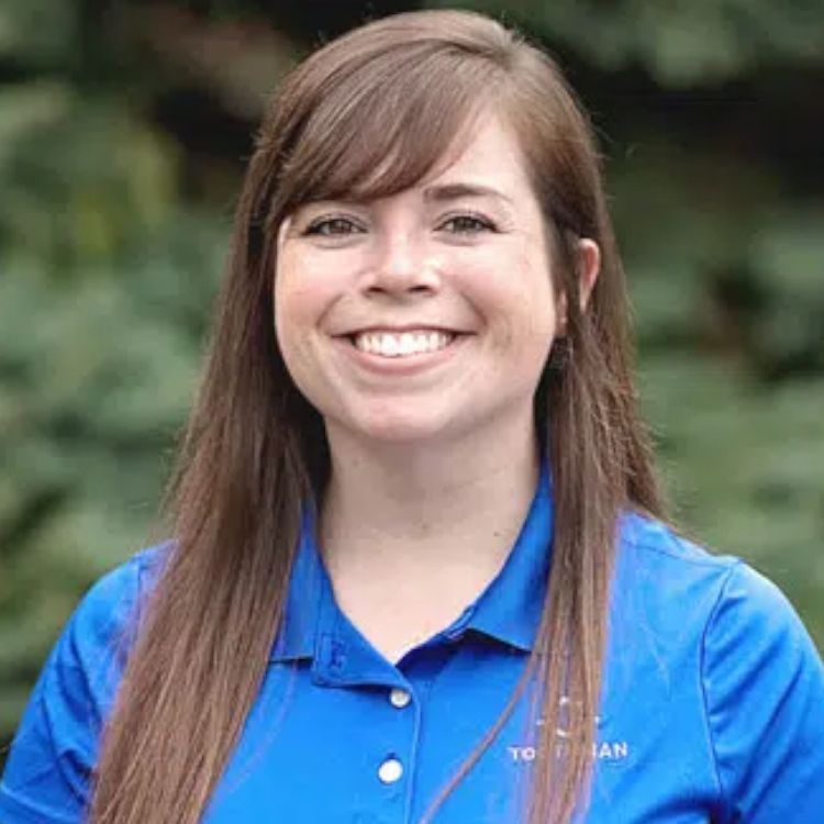 A woman in a blue shirt is smiling for the camera.