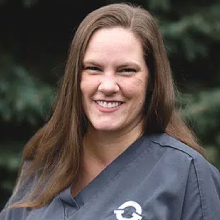 A woman in a scrub top is smiling for the camera.