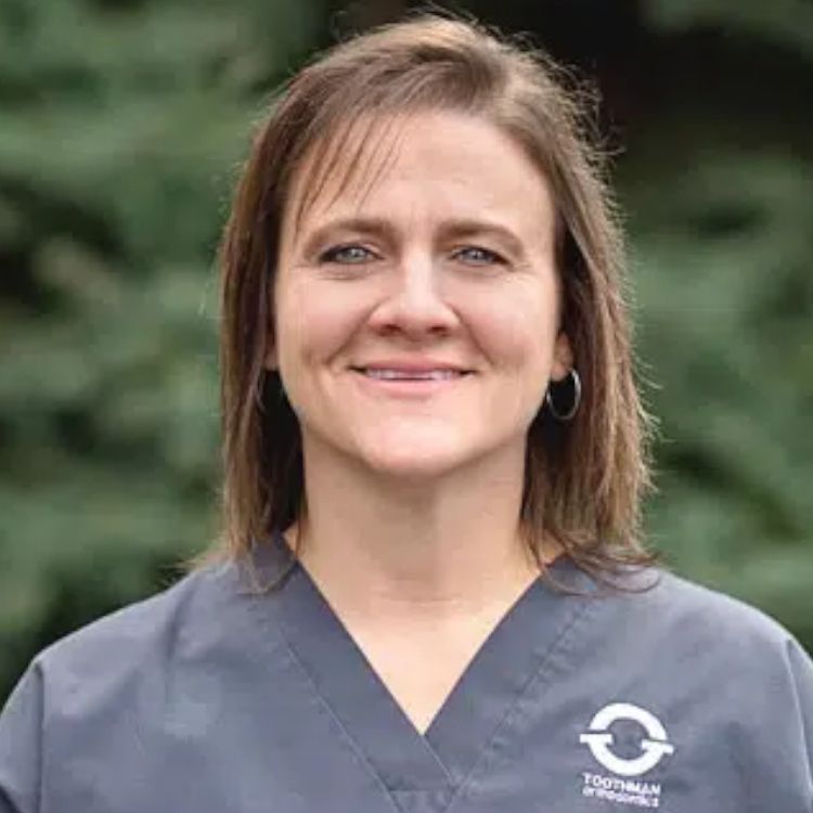 A woman in a scrub top is smiling for the camera.