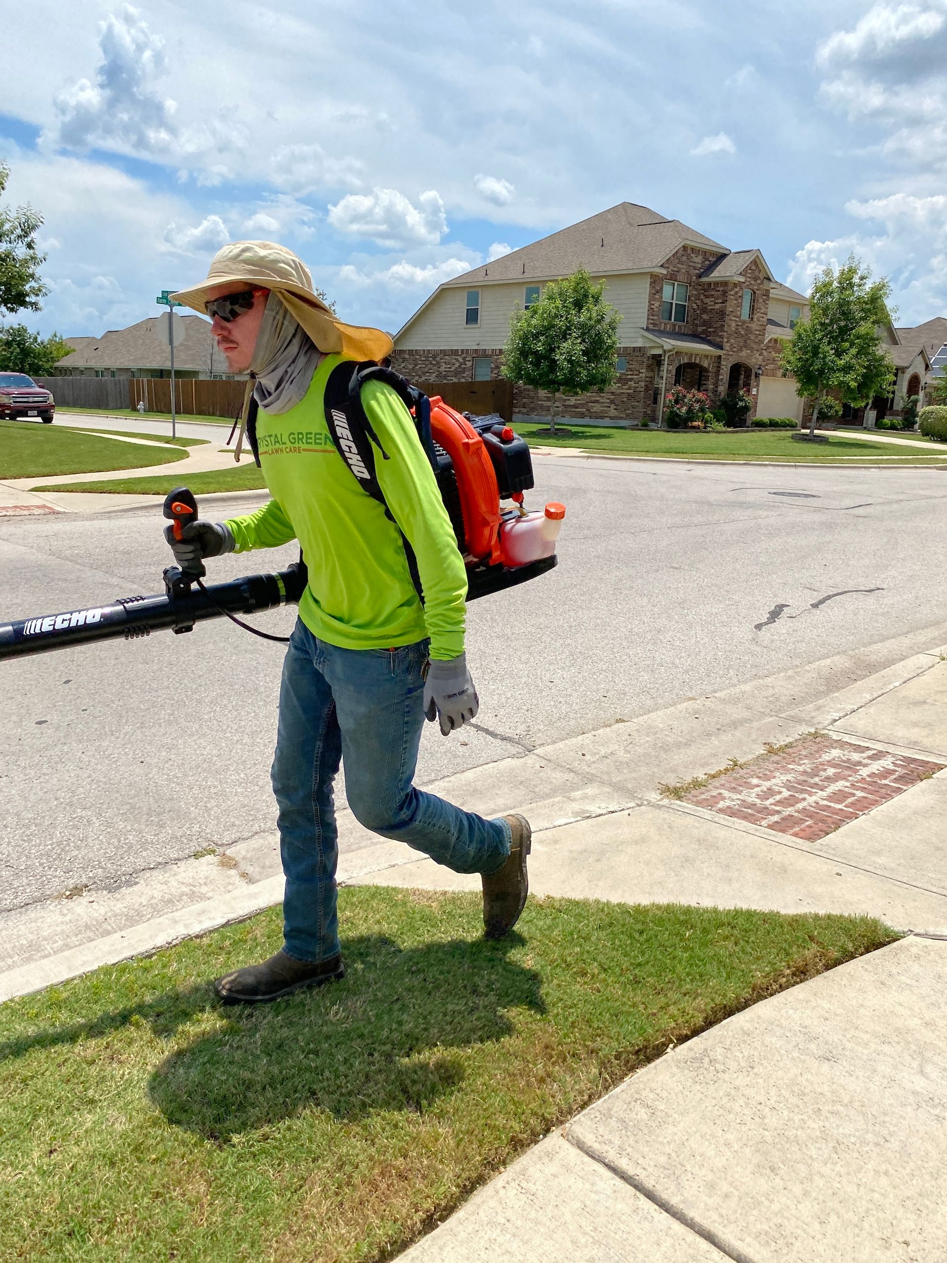 a man is walking down the sidewalk holding a lawn mower .