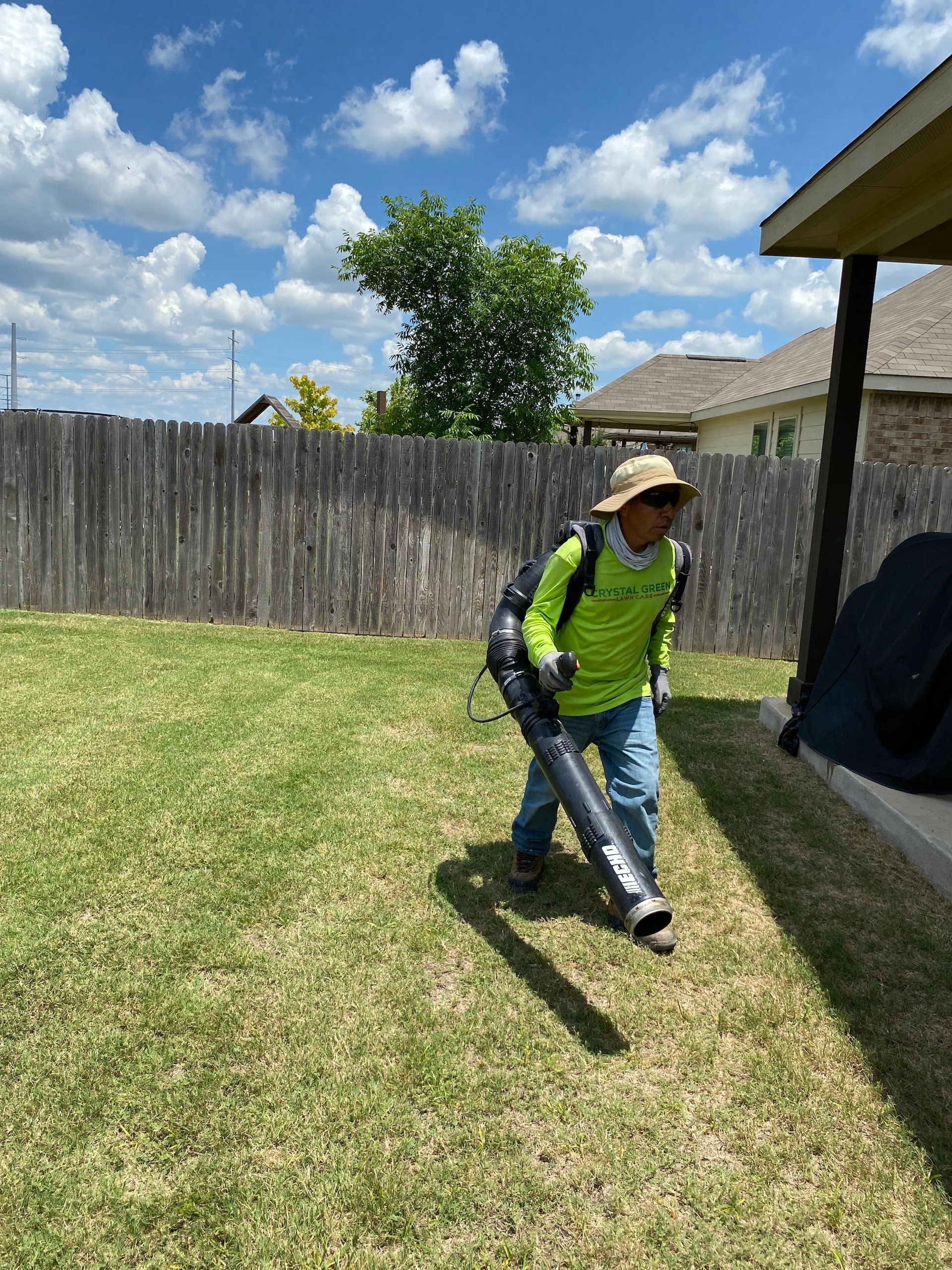 a man is blowing grass in a backyard with a blower .