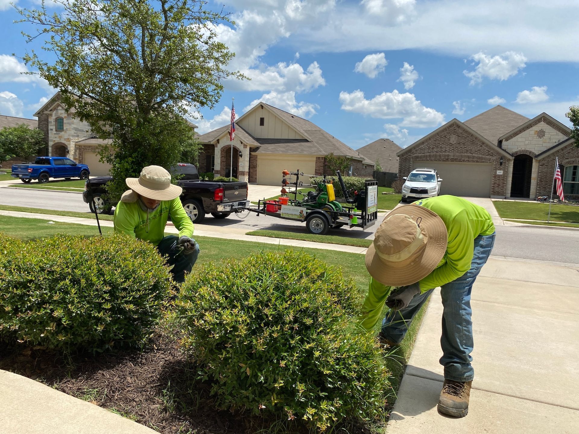 two men are cutting bushes in front of a house .