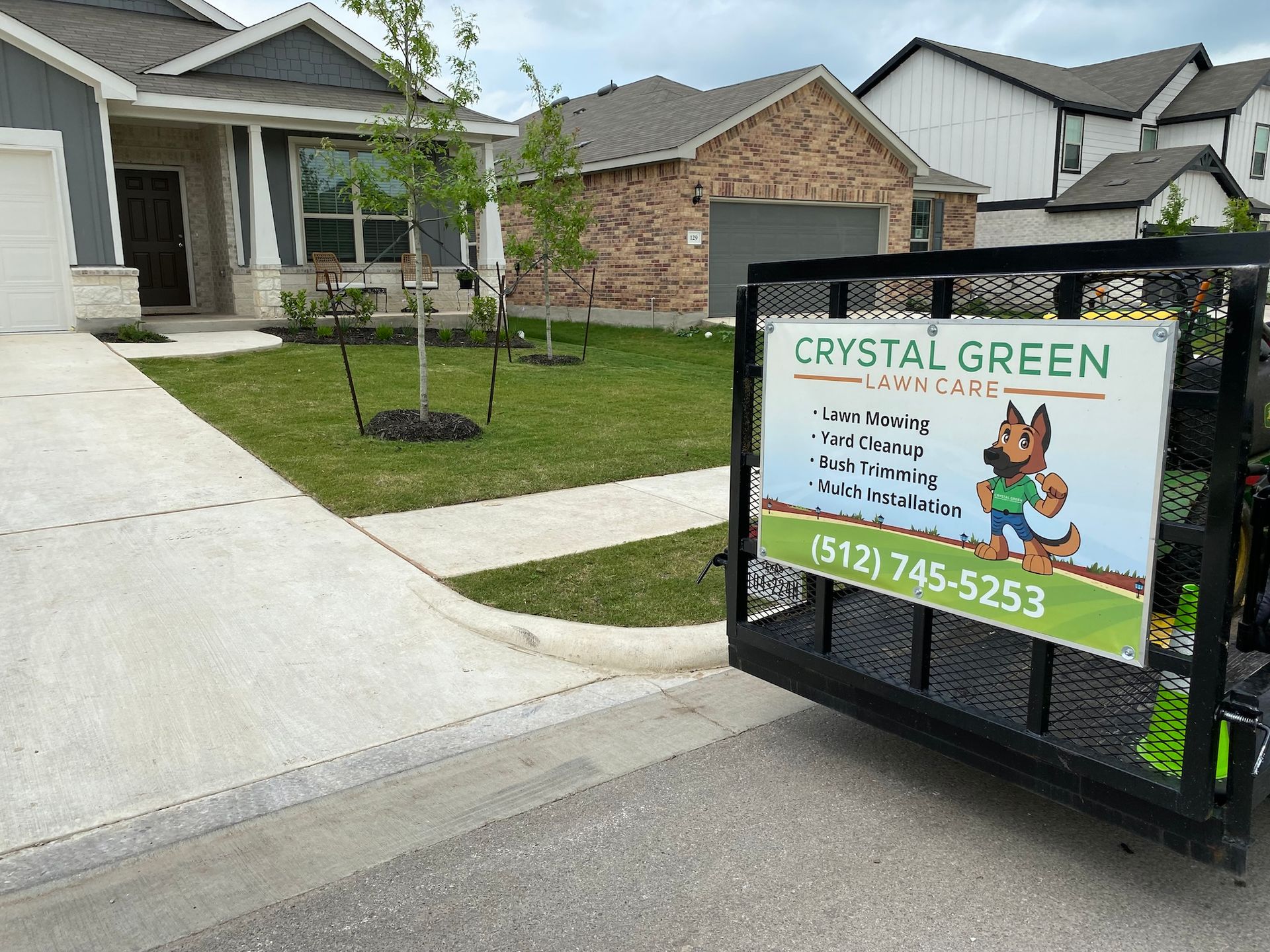 A trailer with a sign on it is parked in front of a house.