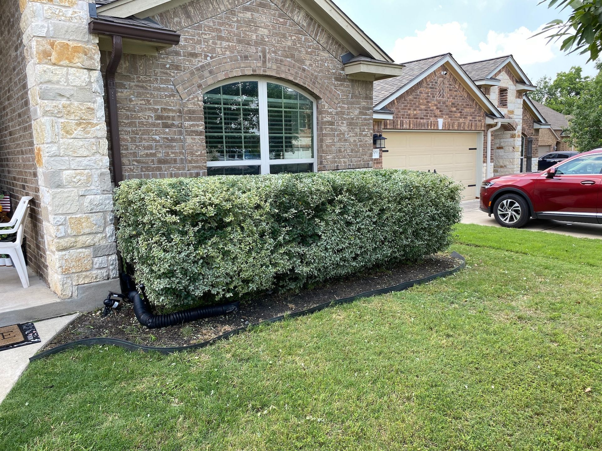 a red car is parked in front of a brick house .