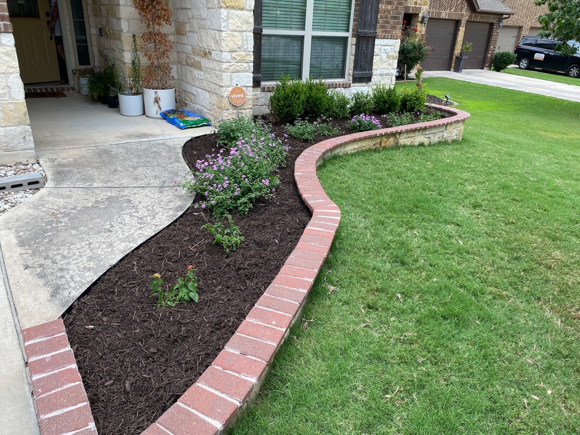 a brick walkway leading to a house with a lush green lawn .