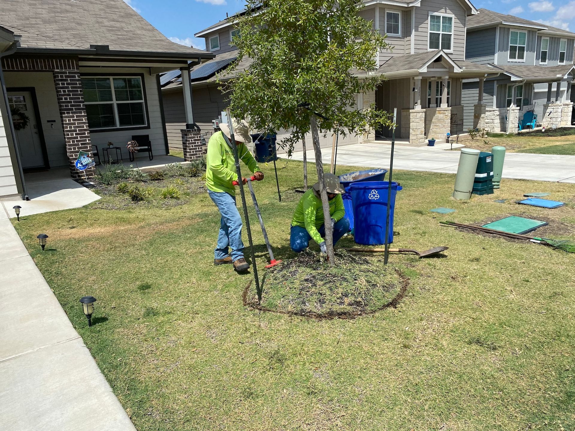 two men are working on a tree in front of a house .