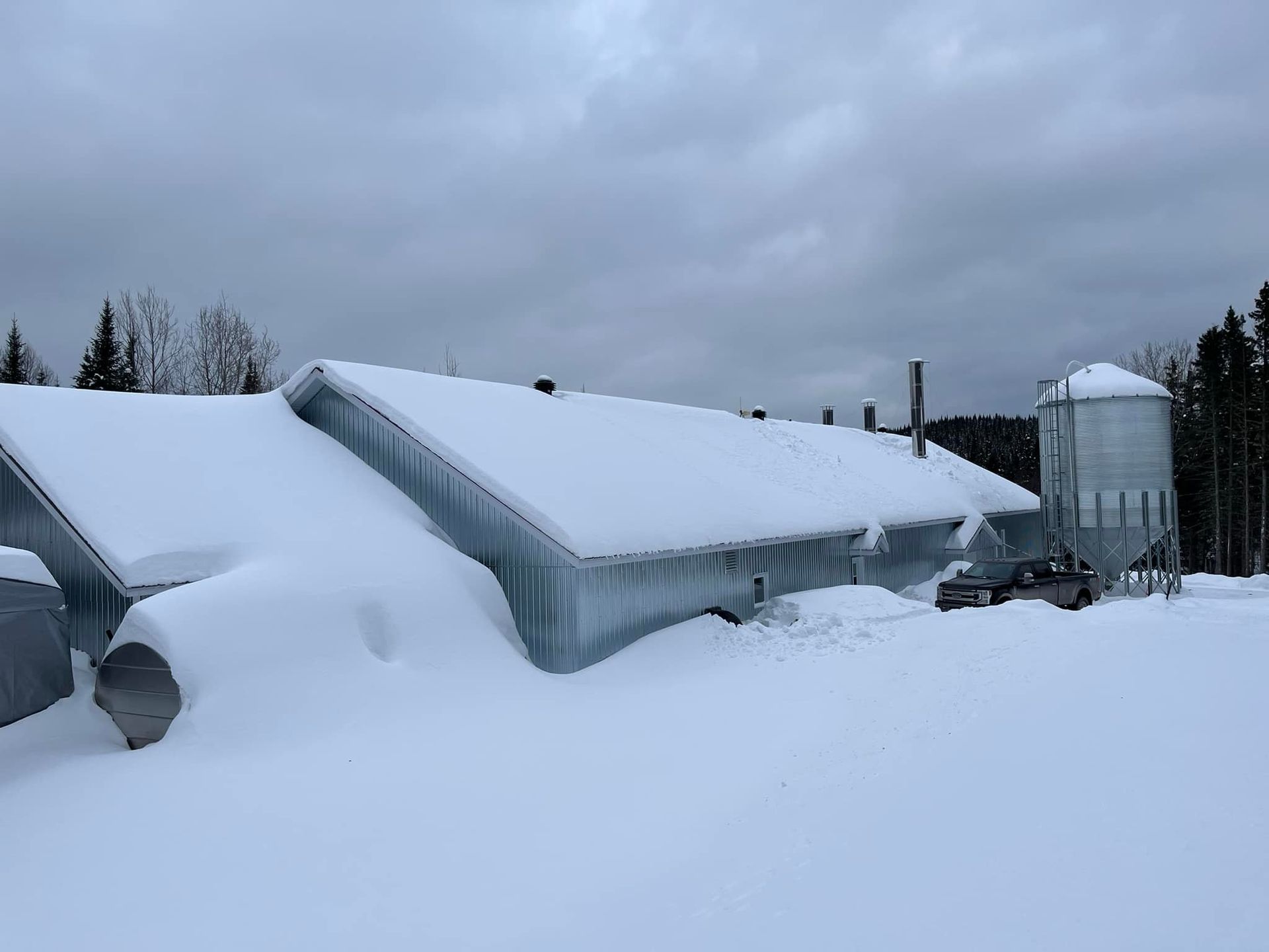 Un grand bâtiment recouvert de neige avec un silo en arrière-plan.