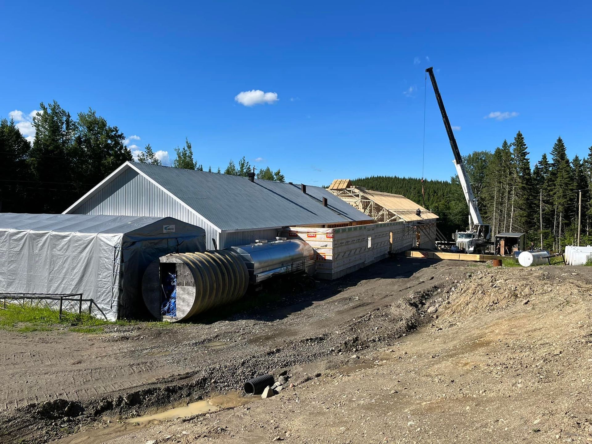 Une grande tente blanche est installée devant un bâtiment en construction.