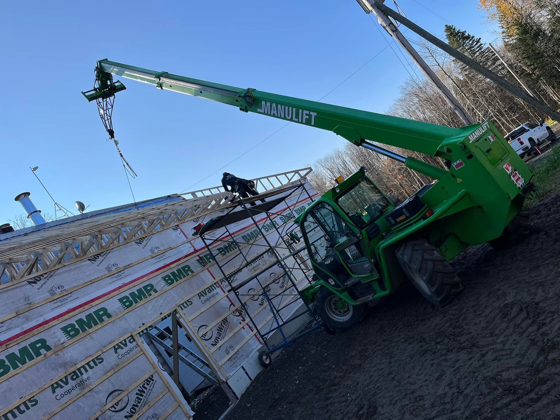 Un chariot élévateur vert est garé devant un bâtiment en construction.